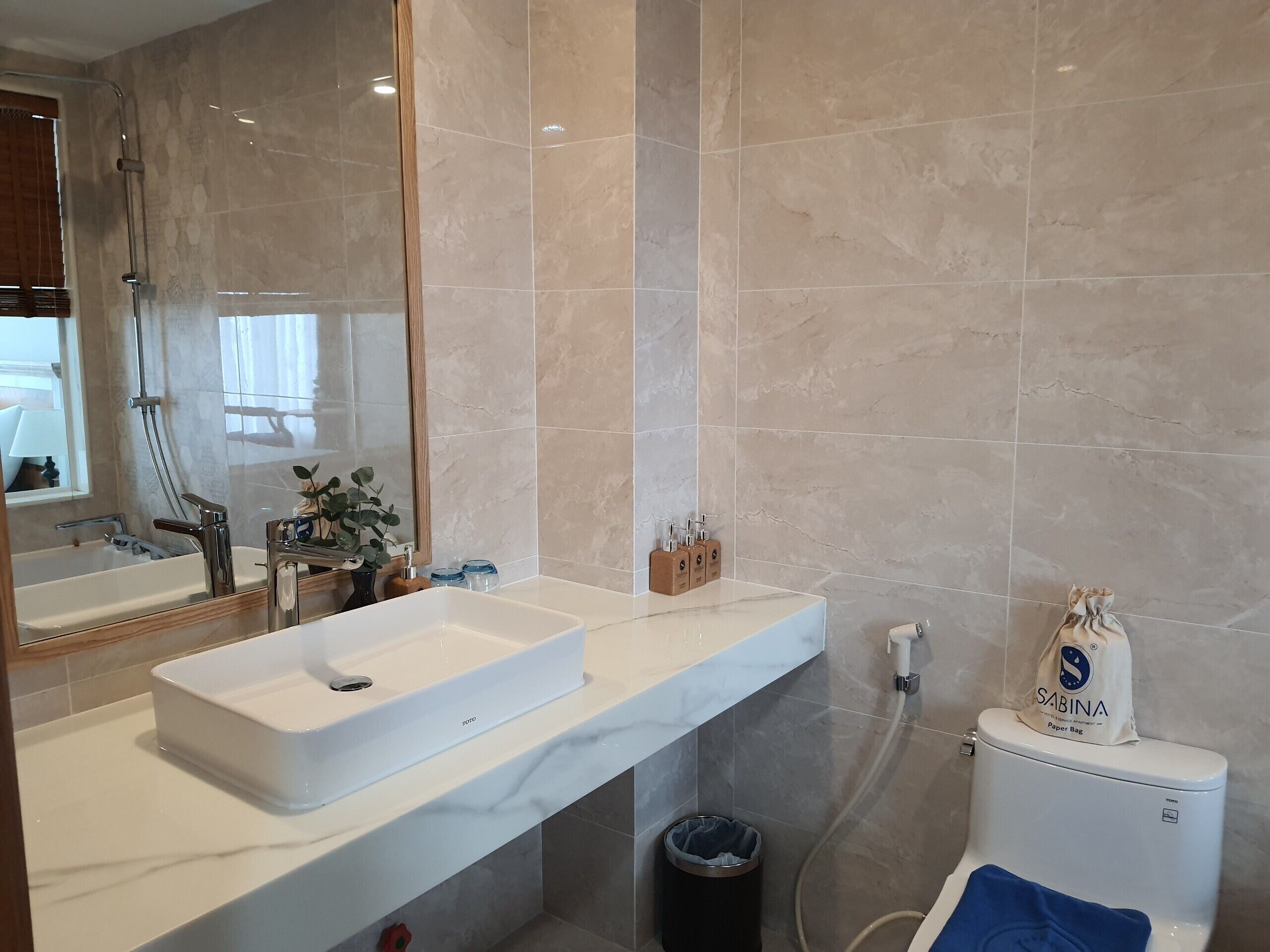 A modern bathroom with a large mirror, a white sink, and a toilet.
