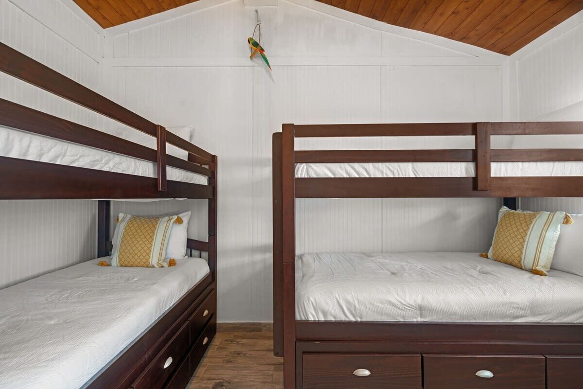 Ein Zimmer mit zwei Etagenbetten, Holzkopfteilen und einer weißen Wand.