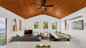 A dining area with a wooden ceiling, a dining table with chairs, a TV, and a guitar on the wall. - Coco Chalet | Villa with private pool and steps from Playa Peñón Brusi (Camuy)