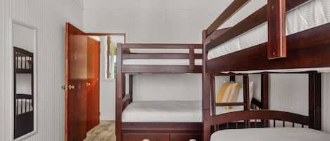 A bunk bed room with a wooden ceiling, white walls, and a wooden floor.