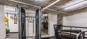Une salle de sport située au premier étage, équipée de matériel de musculation et d’haltères.