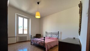 A bedroom with a bed, a chair, a radiator, a window, and a lamp. - In the center of Porretta Terme (Porretta Terme)