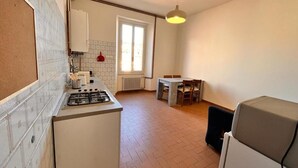 A compact kitchen with a gas stove, a small dining table, and a refrigerator. - In the center of Porretta Terme (Porretta Terme)