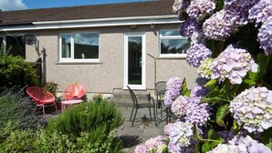 A house with a garden, a red chair, and a table. - Ballyroan - Peaceful Dog Friendly Cottage (Tenby)
