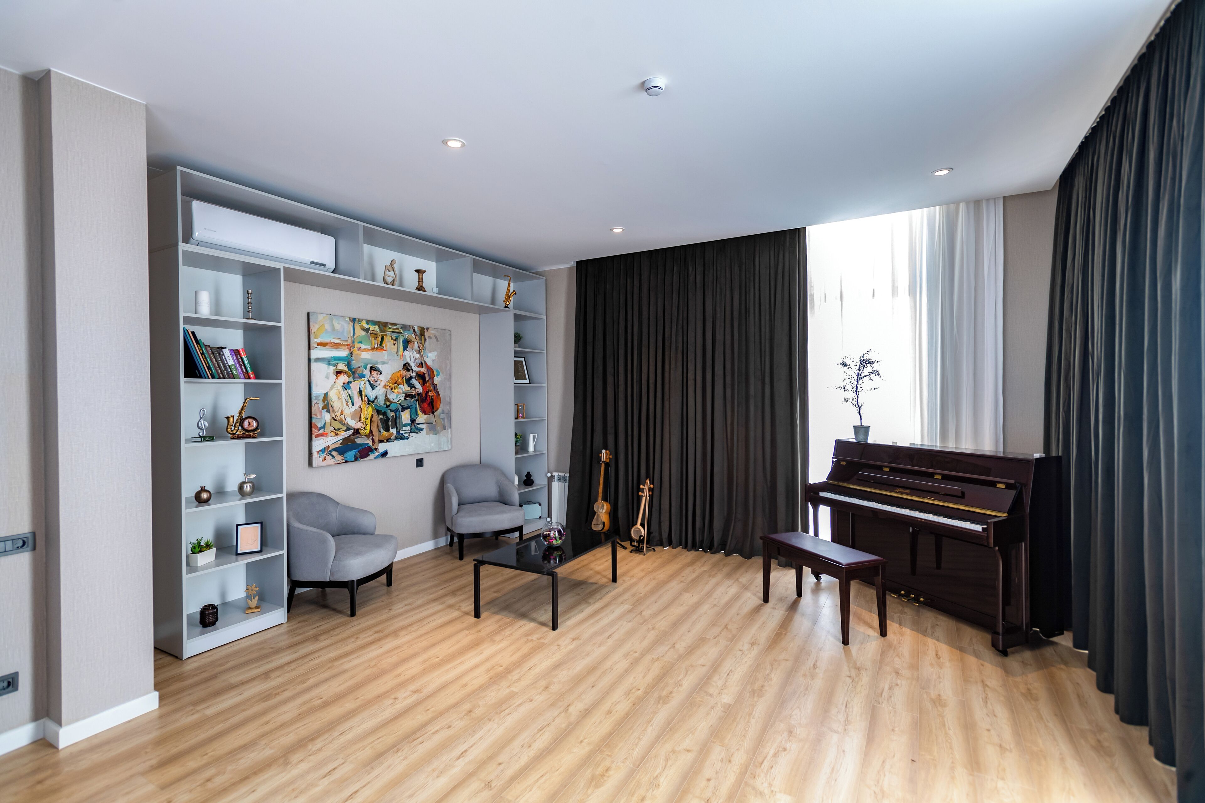A modern living room with a piano, a bookshelf, and a painting.