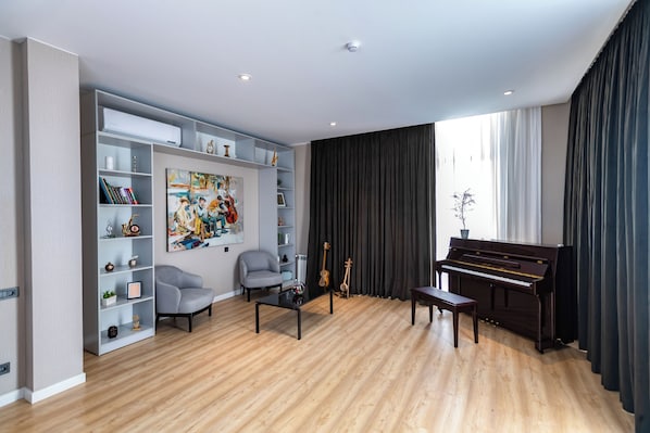 A modern living room with a piano, a bookshelf, and a painting. - Shabran Wellbeing Resort (Shabran)