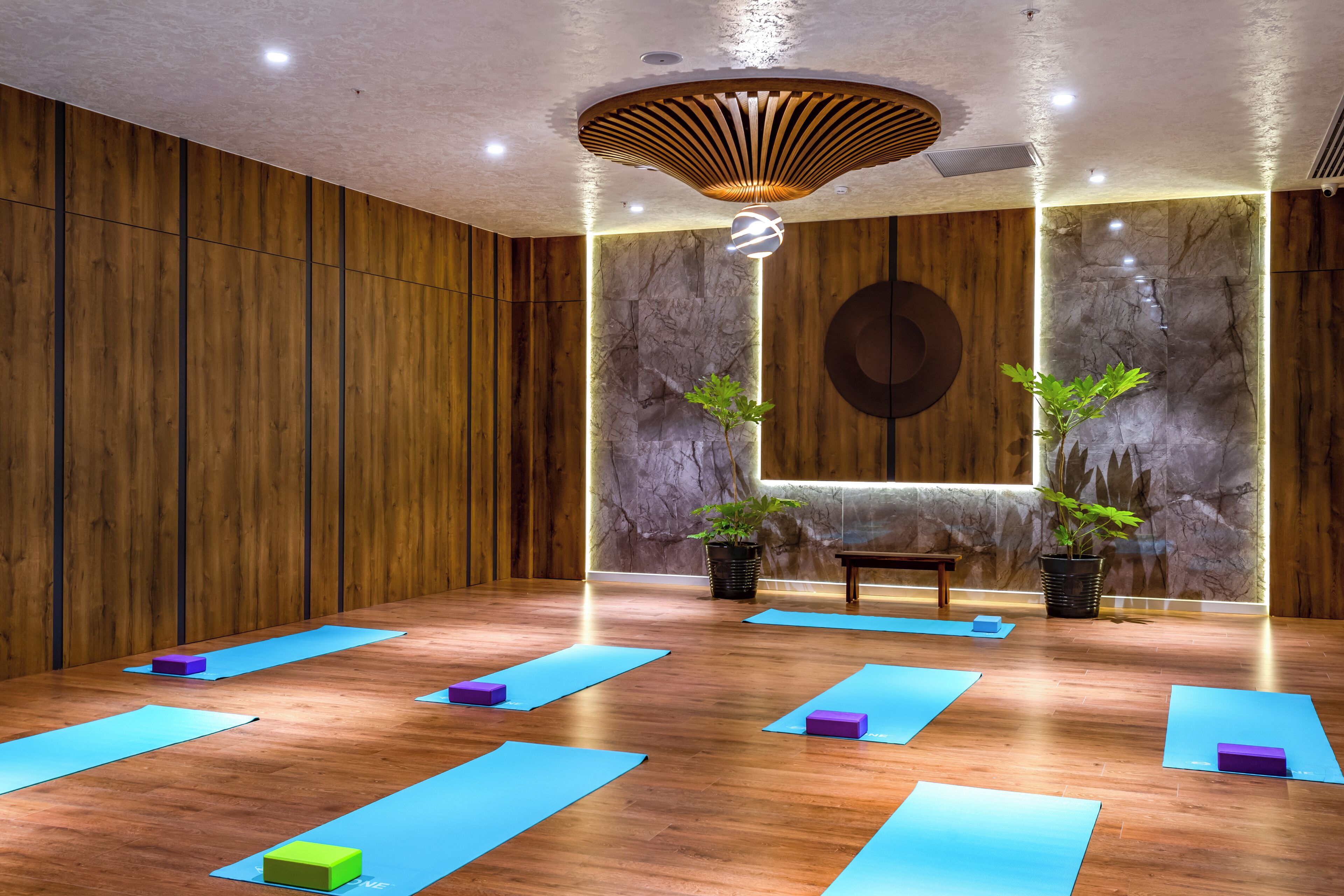 A yoga studio with wooden walls, a marble wall, and a ceiling light fixture.