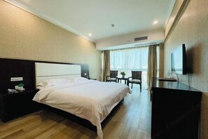 A hotel room with a large bed, a desk, a chair, a television, and a window with curtains. - Jiangxia Hotel (Liuzhou)