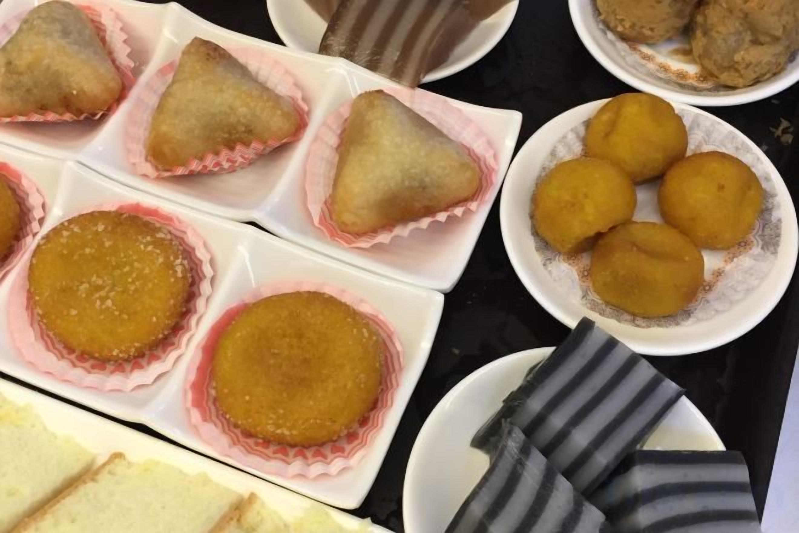 Une variété d’aliments, notamment des pâtisseries triangulaires et rondes, disposées sur des assiettes et dans un plateau.