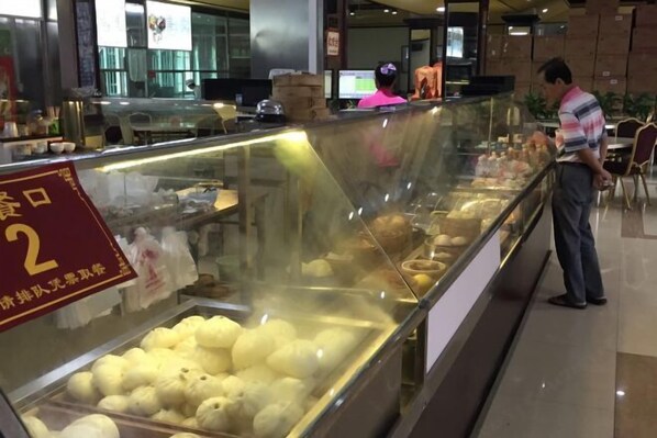 A bakery display case with various baked goods, a sign indicating a special offer, and a person standing nearby.
