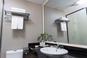 Un baño con lavamanos blanco, un espejo, toallero y zona de ducha.