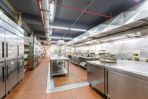A commercial kitchen with stainless steel appliances, a central island, and overhead ventilation. - Jiangxia Hotel (Liuzhou)
