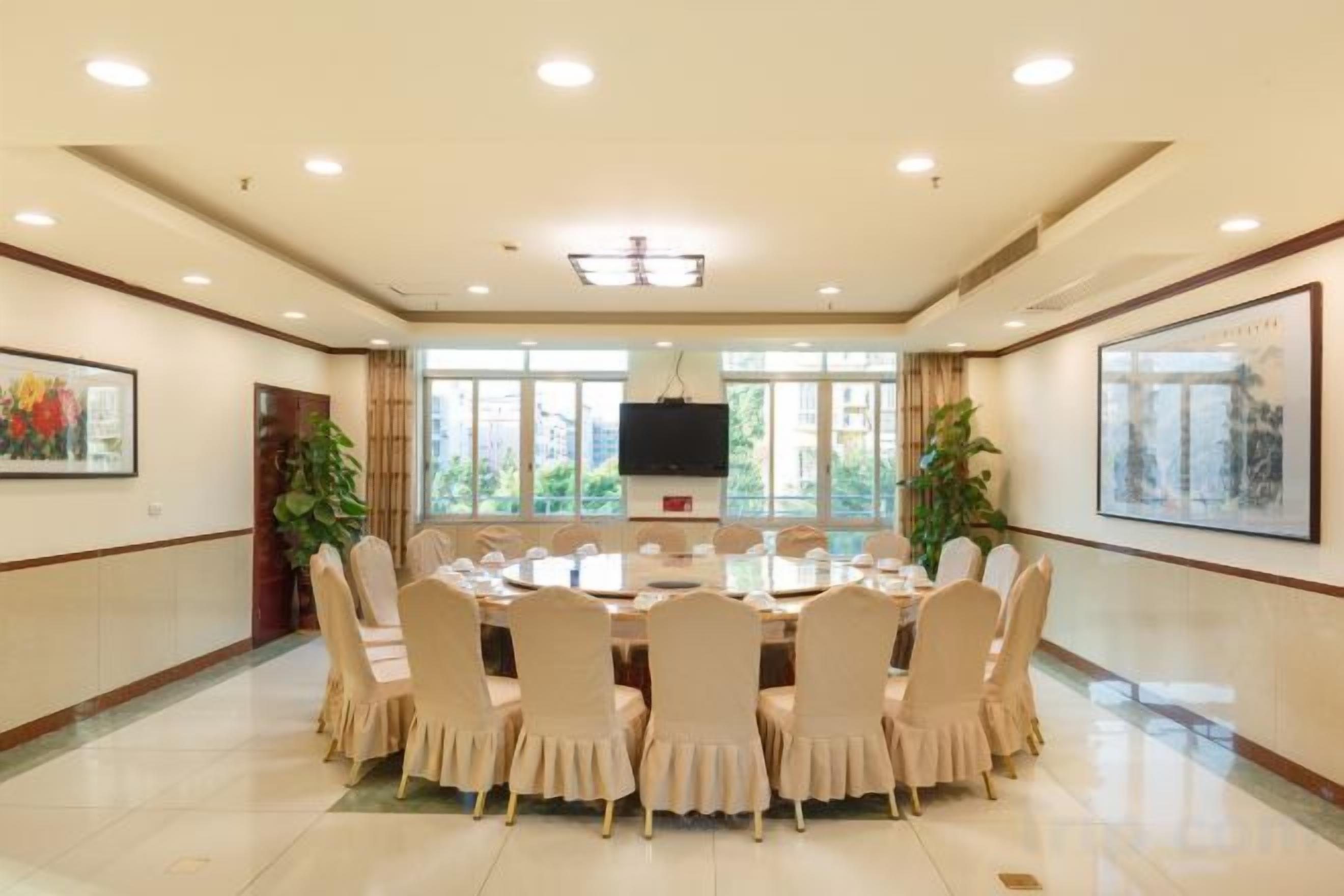 A conference room with a round table, chairs, a flat-screen TV, and framed artwork on the walls.