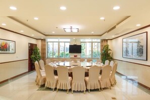 Un salón de conferencias con una mesa redonda, sillas, un televisor de pantalla plana y cuadros en las paredes.