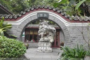 A traditional Chinese building with a stone archway, a stone lion statue, and a tiled roof. - Jiangxia Hotel (Liuzhou)