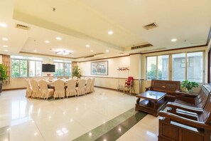 A spacious hotel lobby with a round table and chairs, a sofa set, and large windows. - Jiangxia Hotel (Liuzhou)