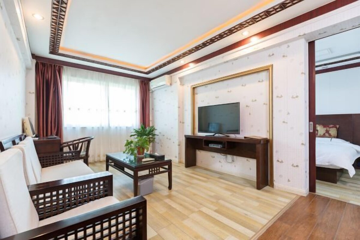 Una habitación de hotel con piso de madera, un sofá, un televisor, un escritorio y una cama.