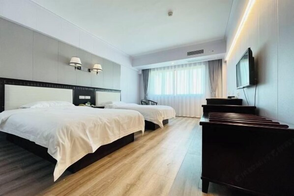 Habitación de hotel con dos camas, televisión de pantalla plana, escritorio y piano.