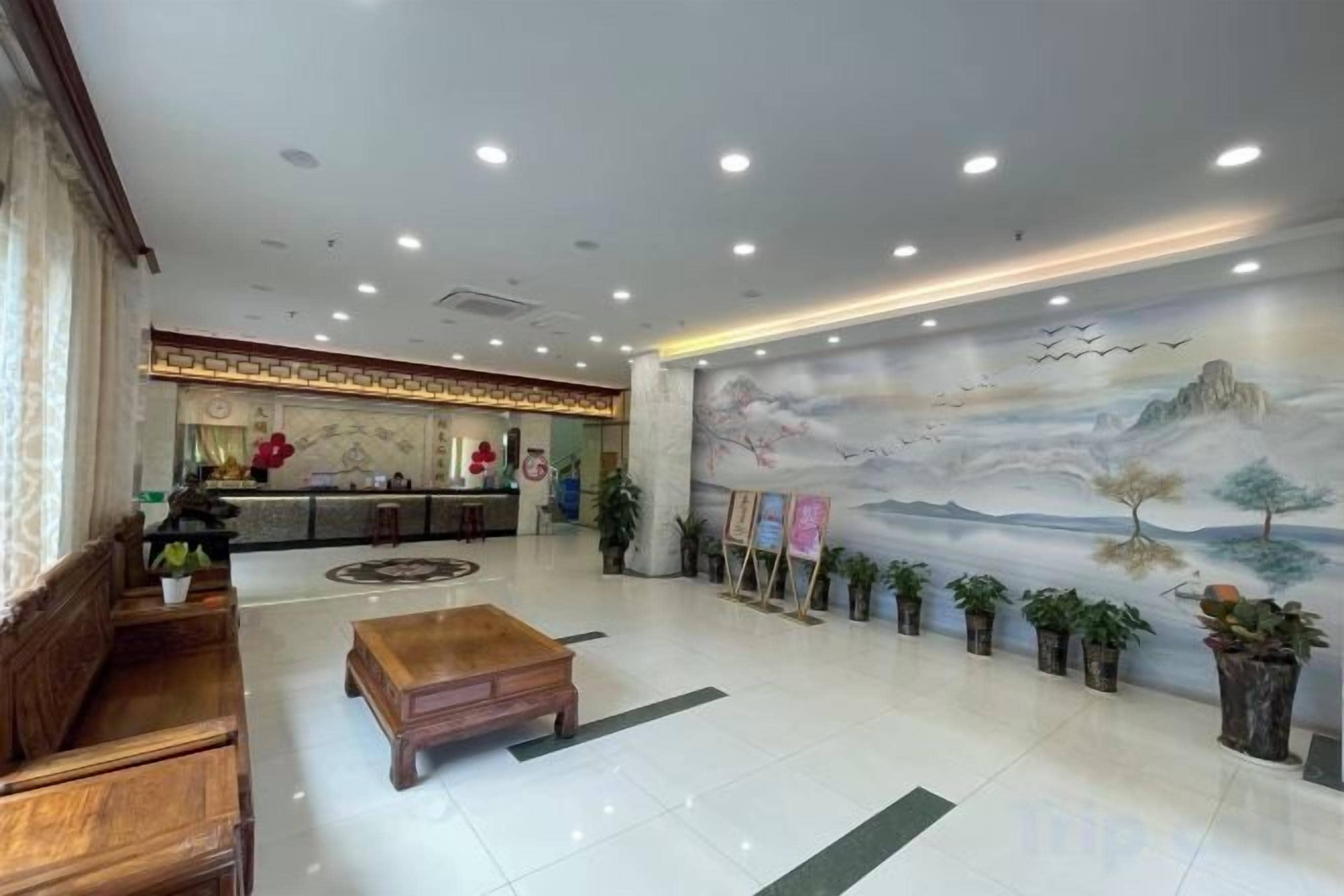 Una hall d'hotel con una reception, area salotto e un murale al muro.