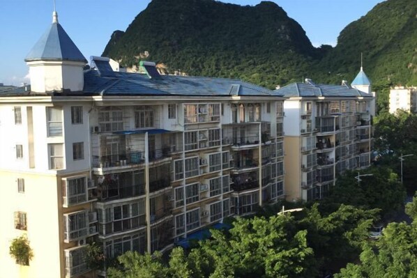 A multi-story hotel with balconies and a mountain backdrop.