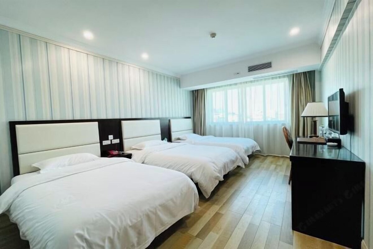 Habitación de hotel con dos camas, un escritorio y un televisor.