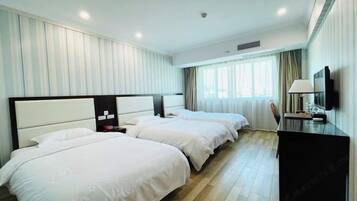 A hotel room with two beds, a desk, and a TV.