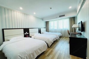 Habitación de hotel con dos camas, un escritorio y un televisor.