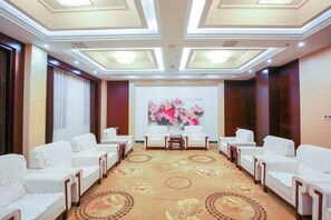 A conference room with a carpeted floor, white chairs, and a table with a floral arrangement.