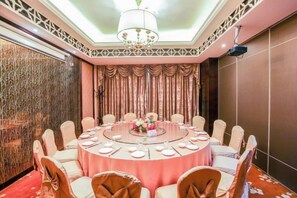Une table ronde entourée de chaises, un lustre et un rideau décoratif en arrière-plan.