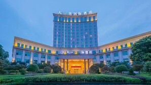 Un hotel de varios pisos con una entrada destacada y una fuente reflectante en primer plano.