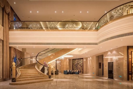 A spacious lobby with a grand staircase, a reception desk, and a high ceiling with decorative lighting.. Liuyiju International Hotel Yongfeng