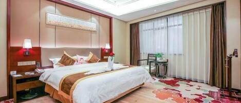 Quarto de hotel com uma cama grande, abajures, uma escrivaninha e vista para o exterior pela janela.