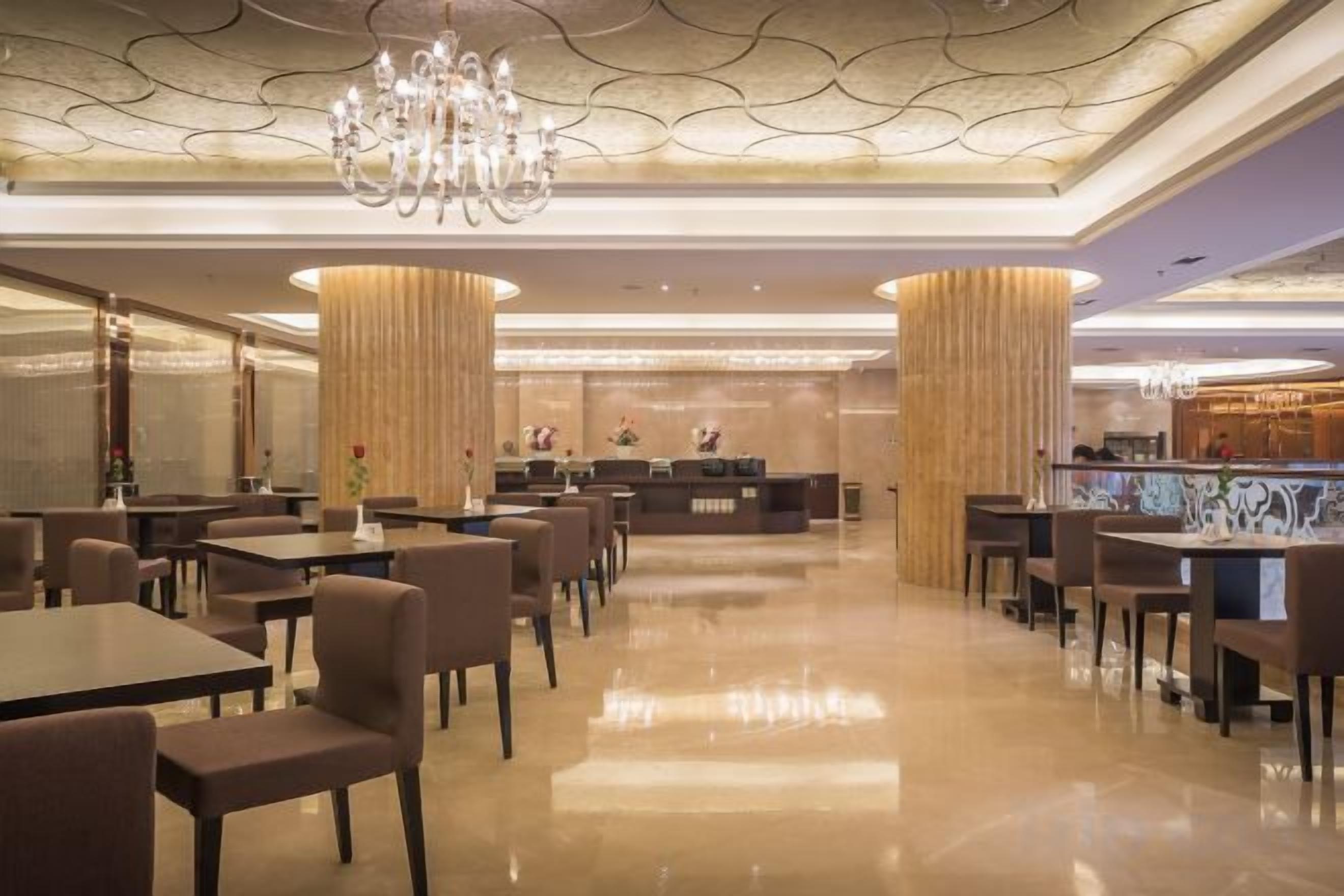 A hotel lobby with a reception desk, seating area, and a chandelier.