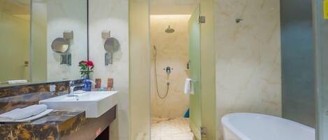 A modern bathroom with a marble vanity, a large mirror, a bathtub, and a glass-enclosed shower area.