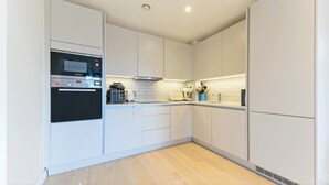 A modern kitchen with white cabinets, a Bosch oven, a coffee maker, and a toaster. - Lovely Luminous 3 Bed Flat, With Secure Ev Parkng (London)