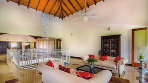 A spacious living area with a high ceiling, a white sofa with red cushions, a coffee table, a bookshelf, and a hanging chandelier. - "srvittinivillas Lmvll7/big Espacius View, Event Priv/ Villa  Resort" (La Romana)
