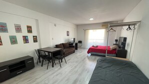 Ein kleines Zimmer mit Bett, Schreibtisch, Stuhl, einem kleinen Tisch und einem Fernseher.