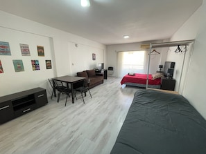 Une pièce de taille modeste comprenant un lit, un bureau, une chaise, une petite table et un téléviseur.