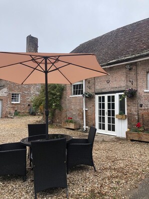 A patio area with outdoor furniture and a large umbrella. - Manor House Mews - Rustic Stable Conversion (Dorchester)