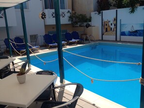 Ett poolområde med blå stolar, ett bord och en avspärrning i form av ett rep.