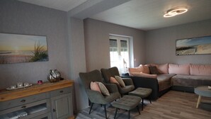 A living room with a sofa, chairs, a coffee table, and a wooden cabinet.