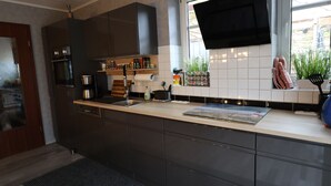 A modern kitchen with dark cabinets, a stainless steel oven, a built-in microwave, and a window with a view of the outdoors.