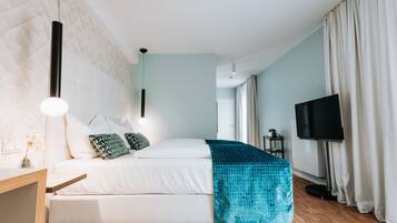 Quarto moderno com cama, televisão e escrivaninha.