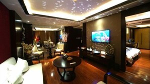 A modern living room with a flat-screen TV, a round coffee table, and a sofa. - Shengzhan Hotel (Chongzuo)
