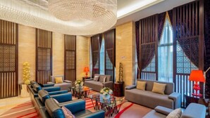 A modern hotel lobby with a seating area, decorative lighting, and a view of the outdoors. - Shengzhan Hotel (Chongzuo)