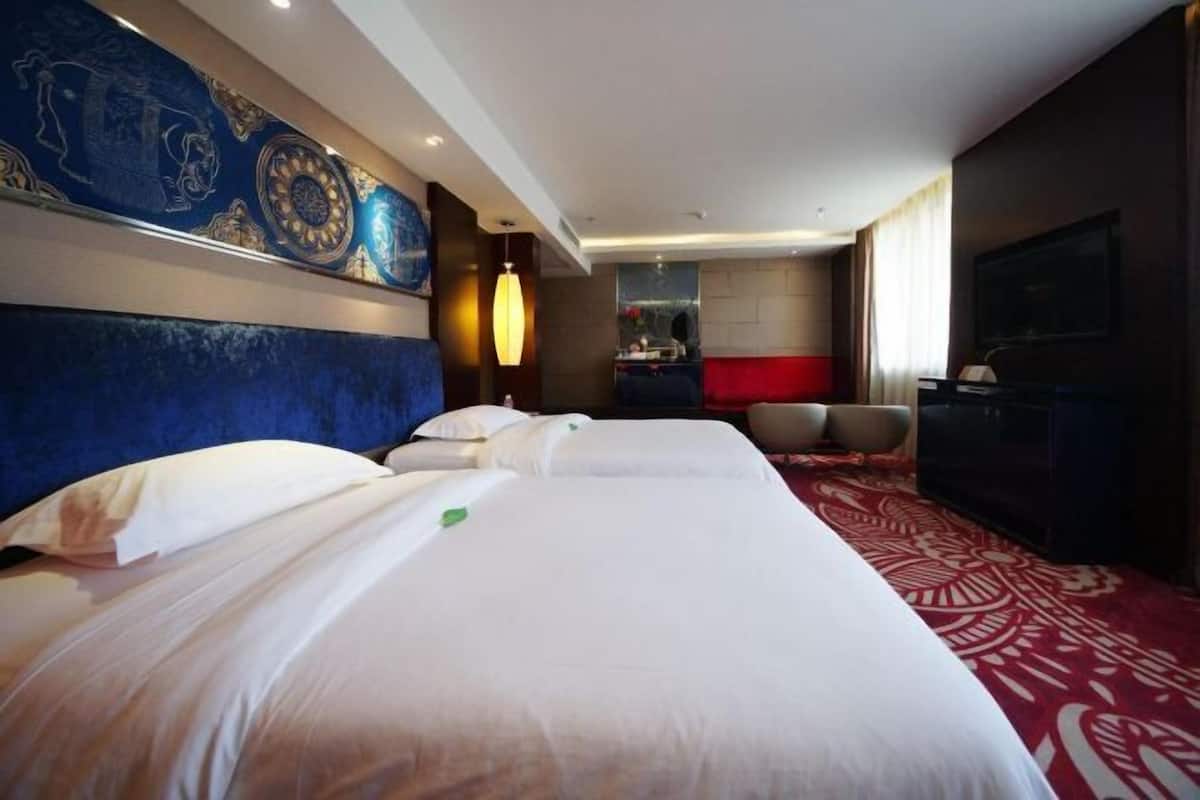 Ein Hotelzimmer mit zwei Betten, einem roten Teppich, einem Fernseher und einer Wand mit blau-goldenem Dekor.