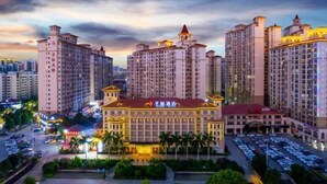 A multi-story hotel with a central building featuring a red roof and multiple balconies. - Shengzhan Hotel (Chongzuo)