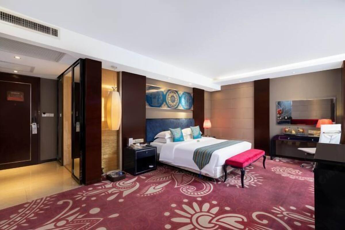Ein Hotelzimmer mit einem großen Bett, einem Schreibtisch, einem Stuhl, einem Nachttisch und einem Kleiderschrank.