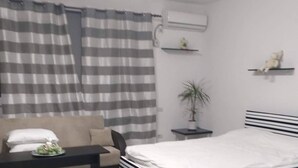 A modern bedroom with a bed, a sofa, a small table, and a potted plant. - Impeccable 1-bed Studio in Roșu (Chiajna)