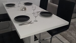 A dining table set with plates, glasses, and cutlery, surrounded by chairs. - Impeccable 1-bed Studio in Roșu (Chiajna)